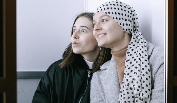 Two friends enjoying photo booth rental experience together indoors.