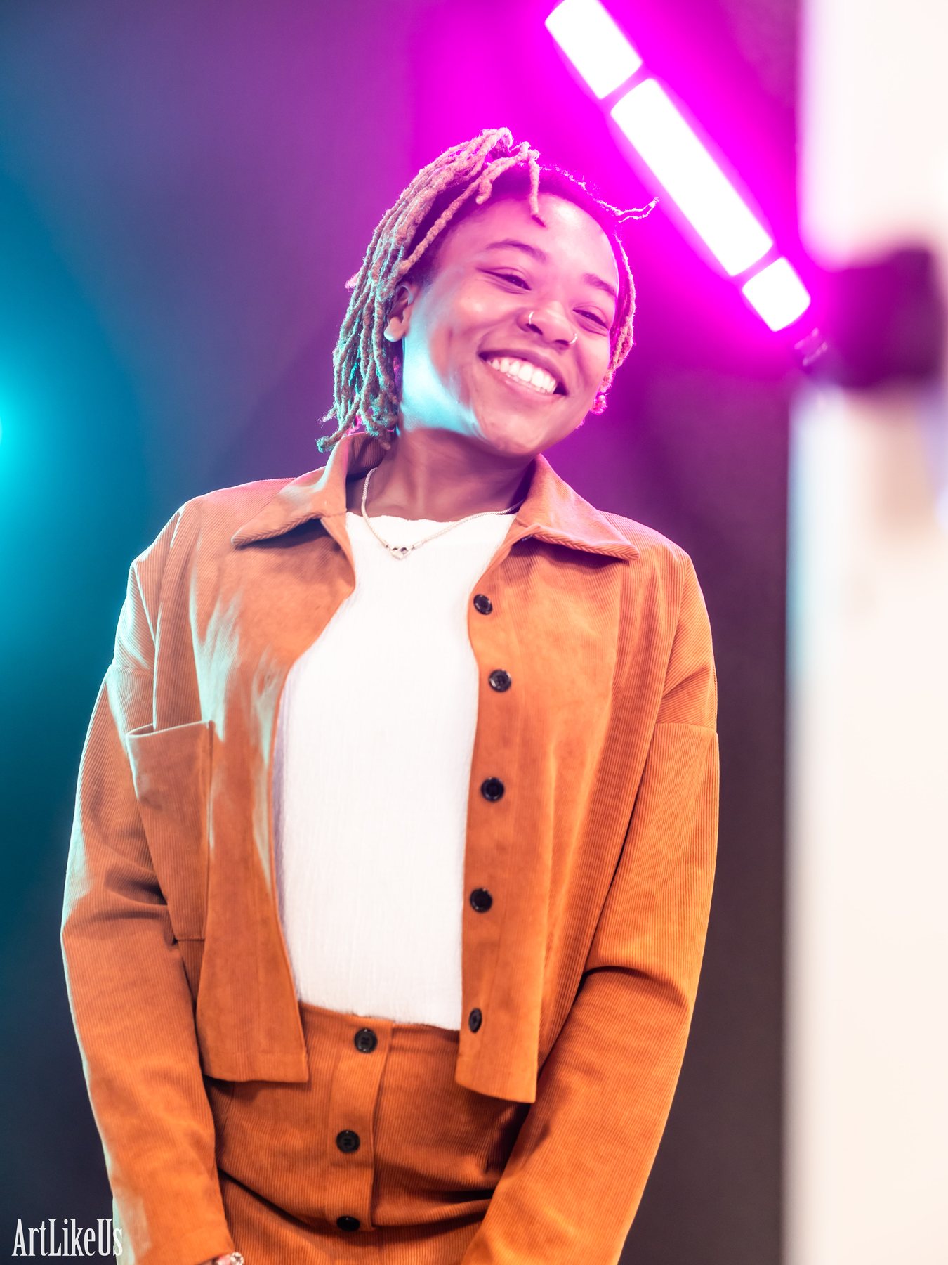 A guest smiling under a glowing magenta and cyan LED wand light trail at the light painting backdrop
