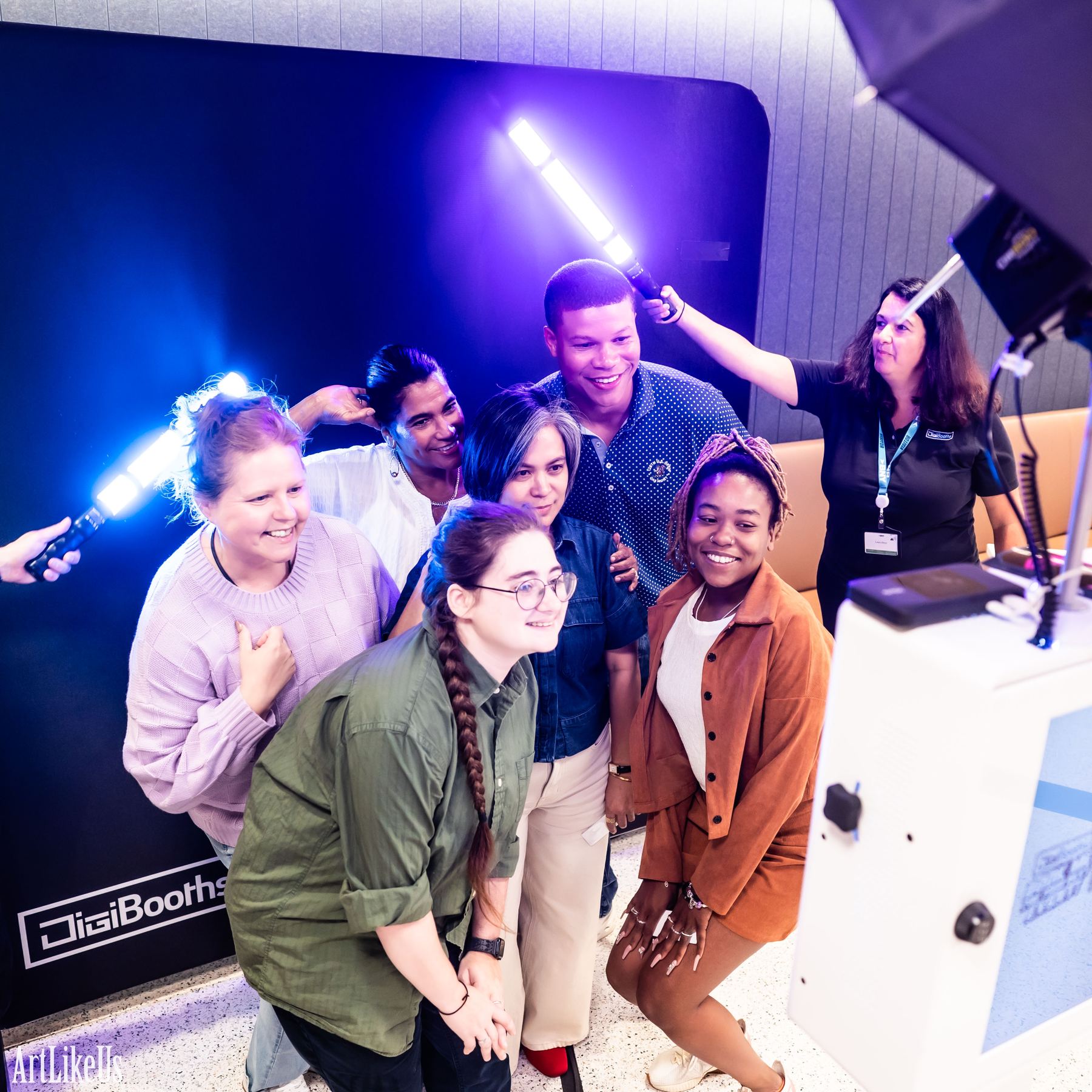 A group of guests laughing together in front of the light painting backdrop after seeing their result