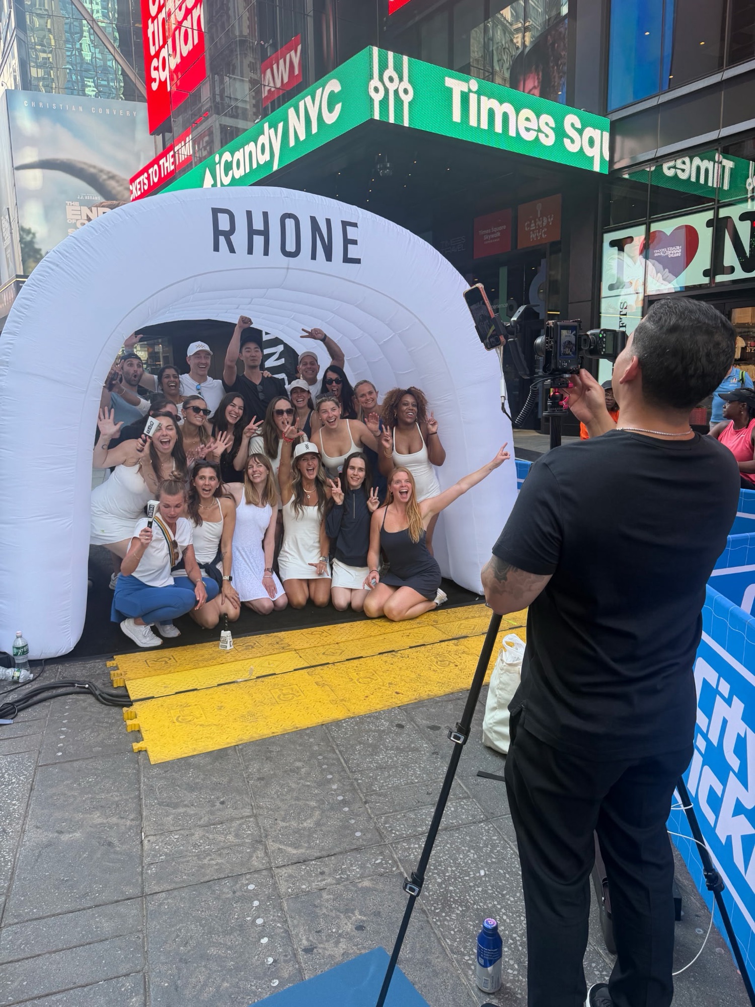 A DigiBooths roaming photographer captures a large group posing in the branded Rhone tunnel in Times Square, NYC