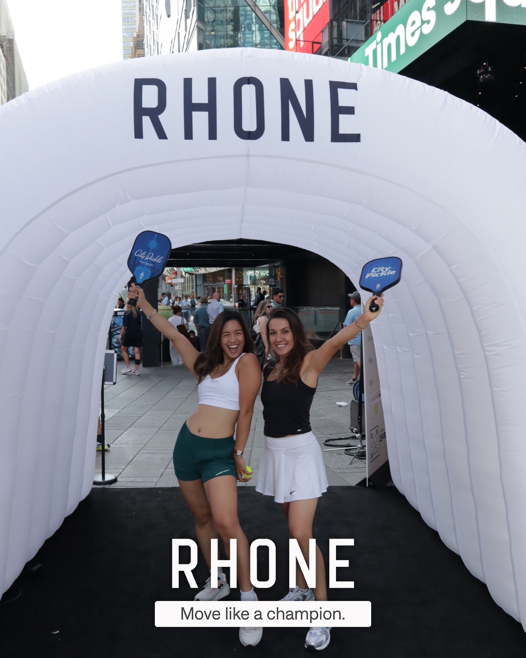 Two guests posing at the entrance of the branded Rhone photo tunnel in Times Square
