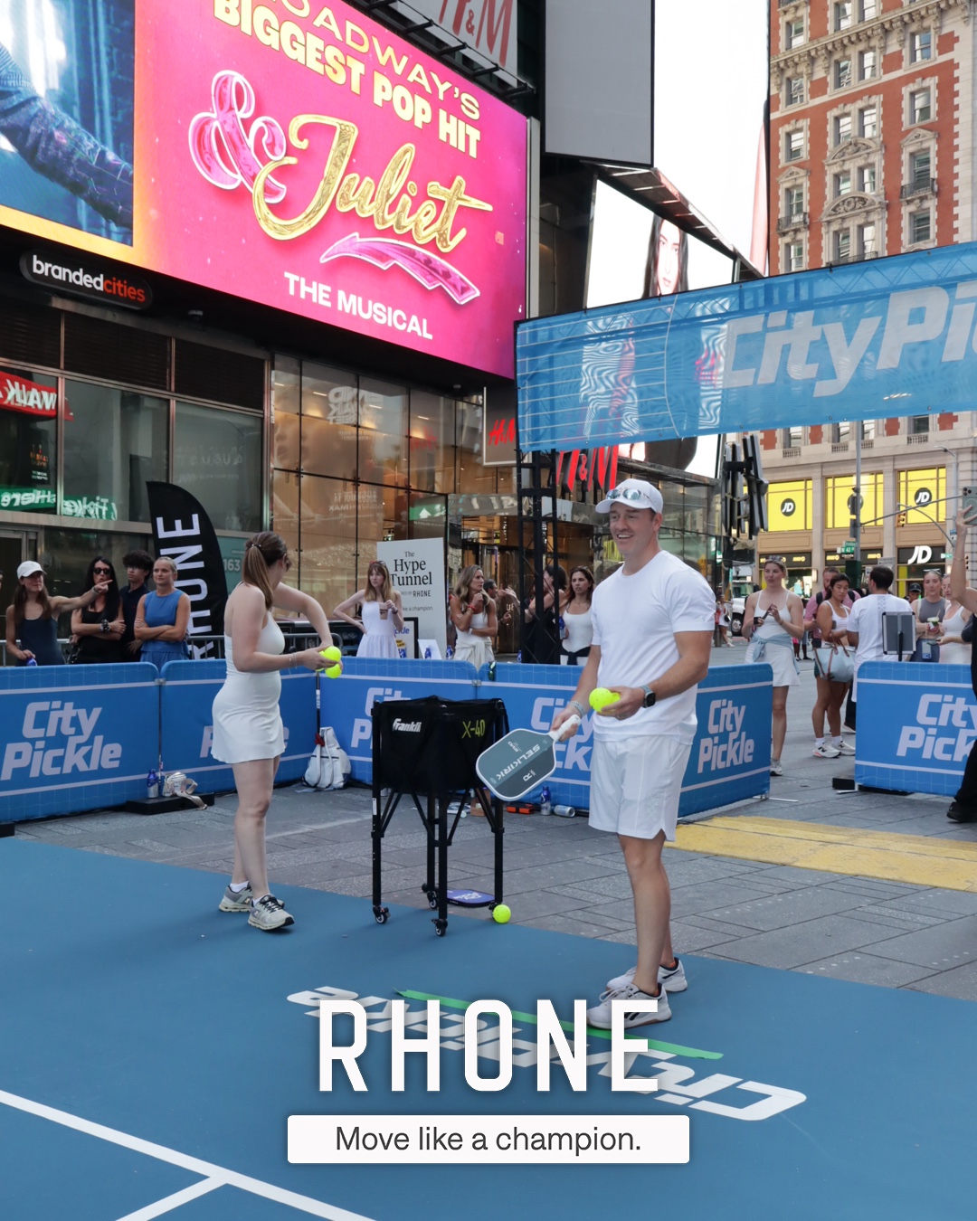 Two players on the City Pickle court against the Times Square skyline, Rhone branded overlay