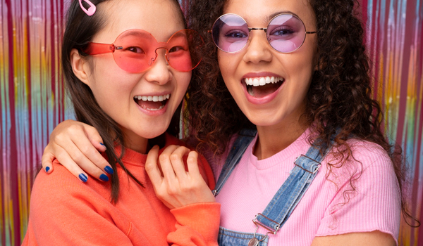 Happy friends with colorful props explaining photo booth rental cost benefits.