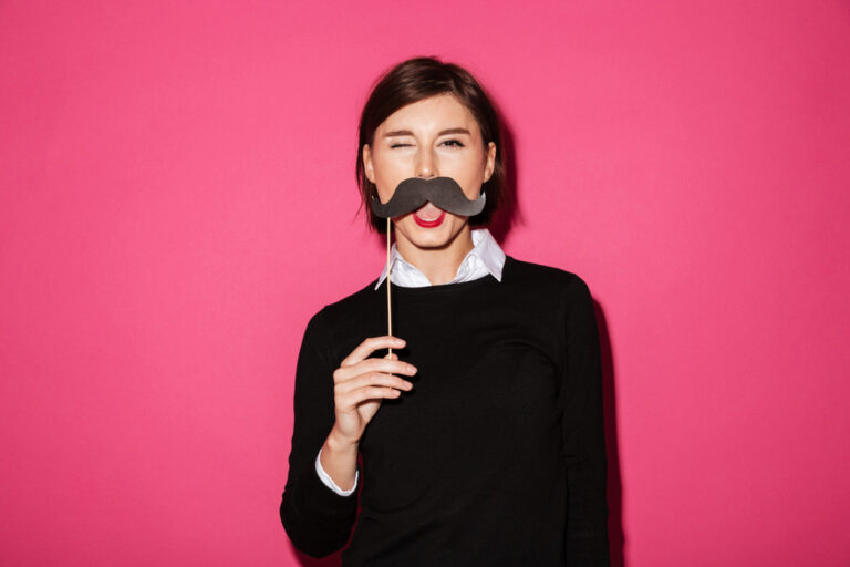 Woman holding mustache prop showing photo booth rental cost value at event.